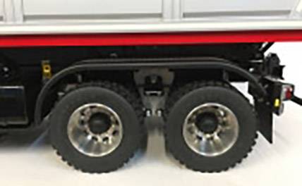 Ciężarówka z czerwoną linią wzdłuż boku nad kołami. Widoczne są tylne koła na gładkiej, białej podłodze.