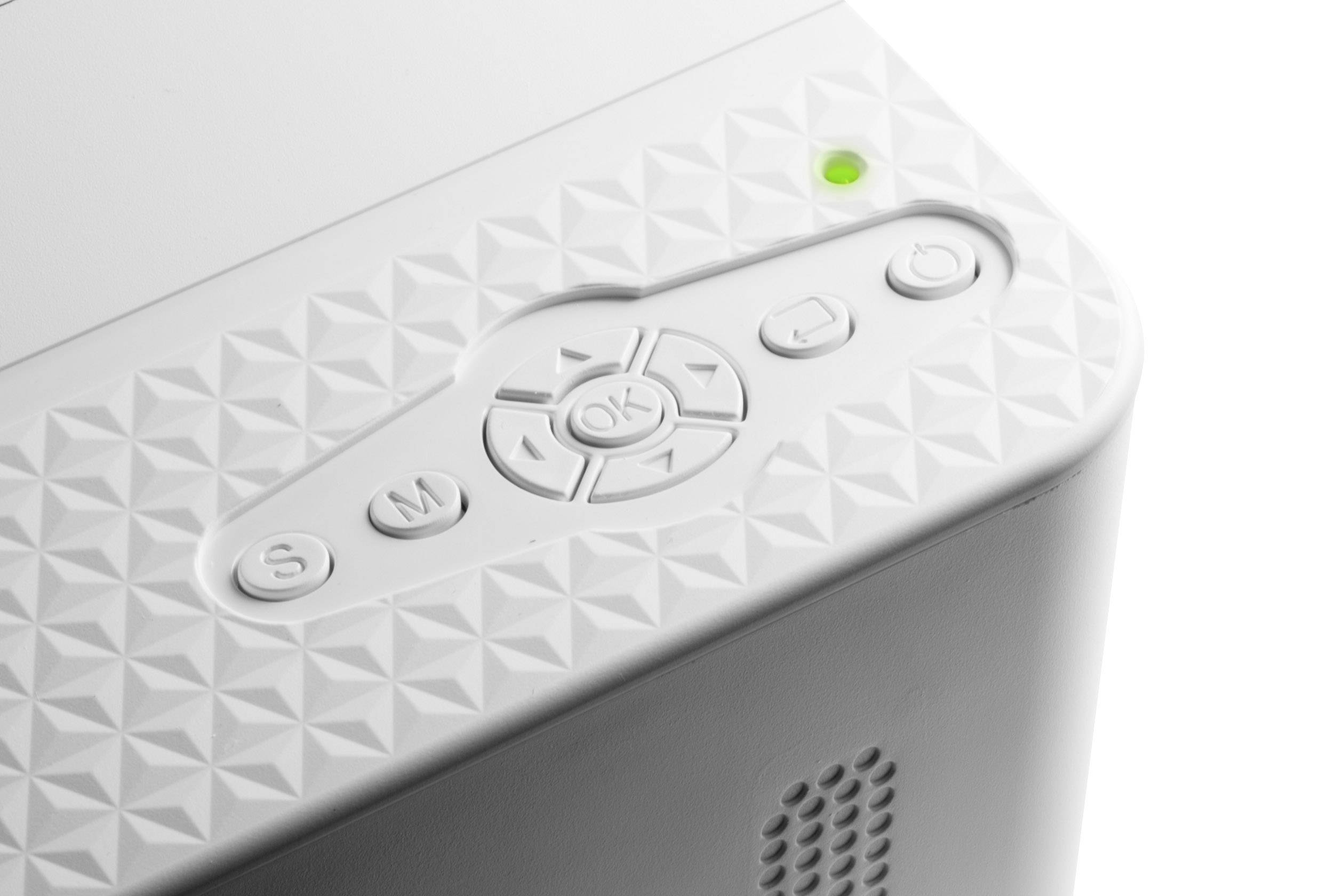 Zdjęcie przedstawia zbliżenie białego urządzenia z teksturowaną powierzchnią i przyciskami sterującymi, w tym przyciskiem 'OK', otoczonym zielonym światłem.