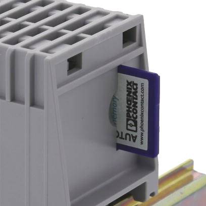 Szare urządzenie elektryczne zamontowane na szynie, z logo Phoenix Contact i etykietą w kolorze niebieskim.