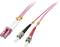 Kabel światłowodowe z różową osłoną i wtyczkami. Dwa złącza LC po jednej stronie, czerwono-czarne wtyki ST po drugiej stronie.