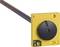 Żółty, kwadratowy moduł sensoryczny z czarnym, okrągłym pokrętłem, podłączony do czarnego przewodu. Przeznaczony do zastosowań przemysłowych.