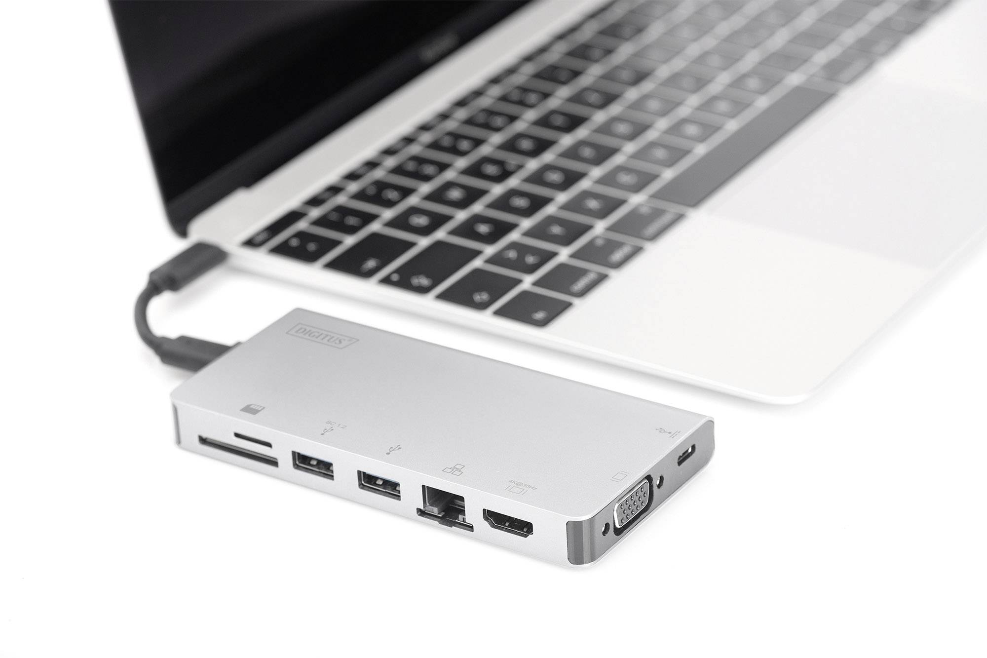 Laptop z podłączoną stacją dokującą USB-C. Stacja dokująca posiada wiele portów, w tym USB, HDMI i Ethernet.
