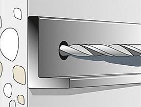 Wiertło przebija ścianę z kamieniami.