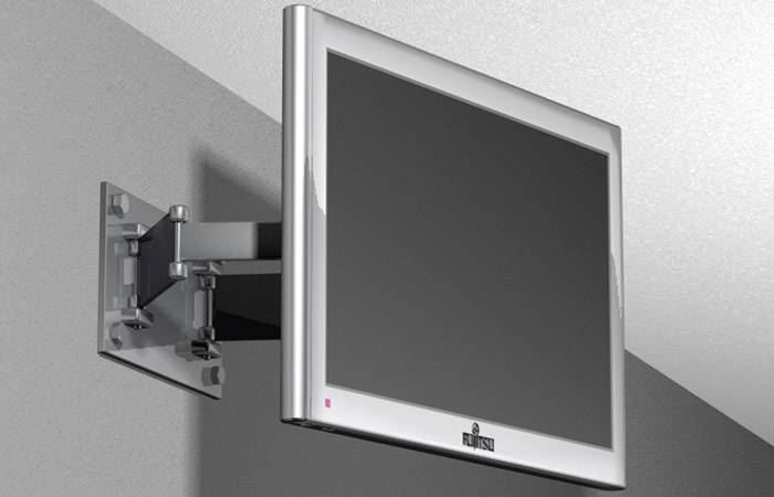 Płaski telewizor zamocowany na uchwycie ściennym, który nie wyświetla żadnej treści na ekranie, na tle ściany w jasnym odcieniu szarości.