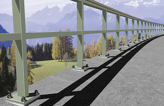 Betonowy most ze stalową balustradą rozciąga się nad pagórkowatym krajobrazem, w tle las i oddalone góry pod jasnym niebem.