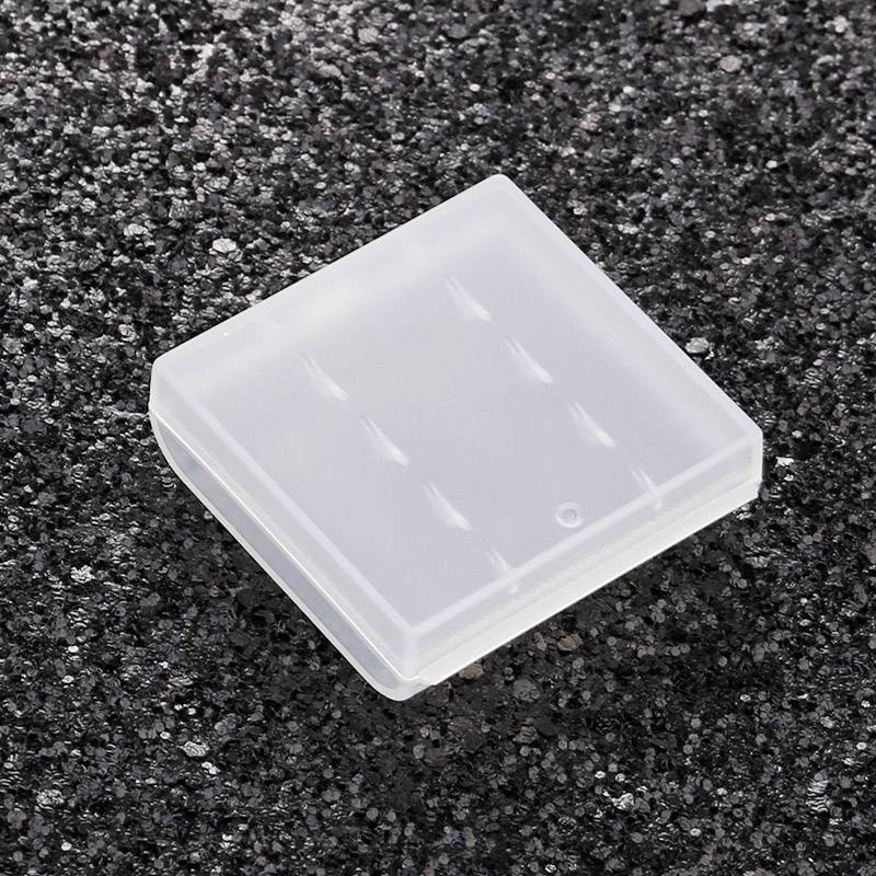 Przezroczysty, kwadratowy futerał z tworzywa sztucznego leży na czarnej powierzchni. Jest zamknięty i pusty.