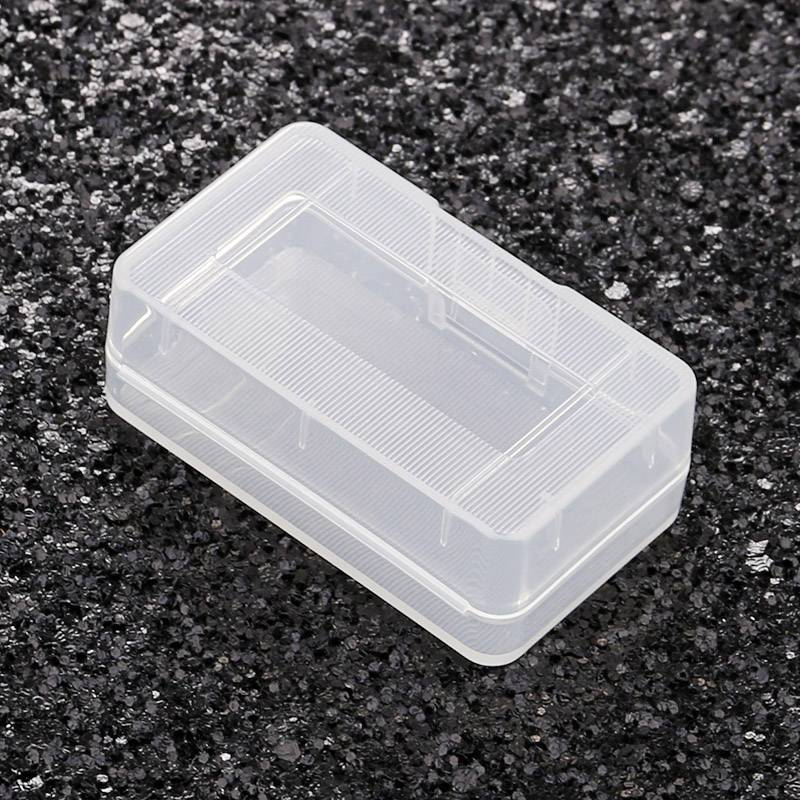 Mała, przezroczysta plastikowa skrzynka z pokrywką, umieszczona na czarnym, ziarnistym podłożu. Idealna do przechowywania małych przedmiotów.