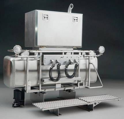 Srebrny zbiornik powietrzny z dwoma wężami i skrzynką na górze, prawdopodobnie będący częścią większej maszyny lub pojazdu.