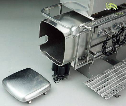 Prostokątne, metalowe urządzenie z okrągłym wylotem po prawej stronie. Obok zdejmowana pokrywa i ryflowana nakładka.