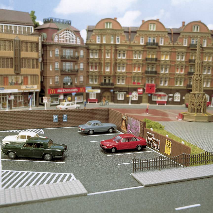 Miniaturowy widok miasta z samochodami na parkingu, historycznymi budynkami i McDonald's w tle.