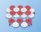 Czerwone i białe plastikowe koła zębate o różnych rozmiarach leżą na niebieskiej powierzchni. Są ułożone w nieregularny sposób i wydają się być częścią systemu modułowego.