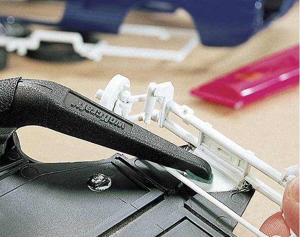 Zbliżenie narzędzia oddzielającego białą część plastikową od ramy odlewniczej. W tle widoczne są kolejne elementy modelu.