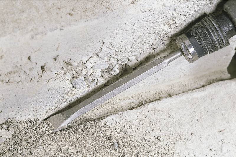 Dłuto usuwa zaprawę między dwoma kamiennymi płytami.