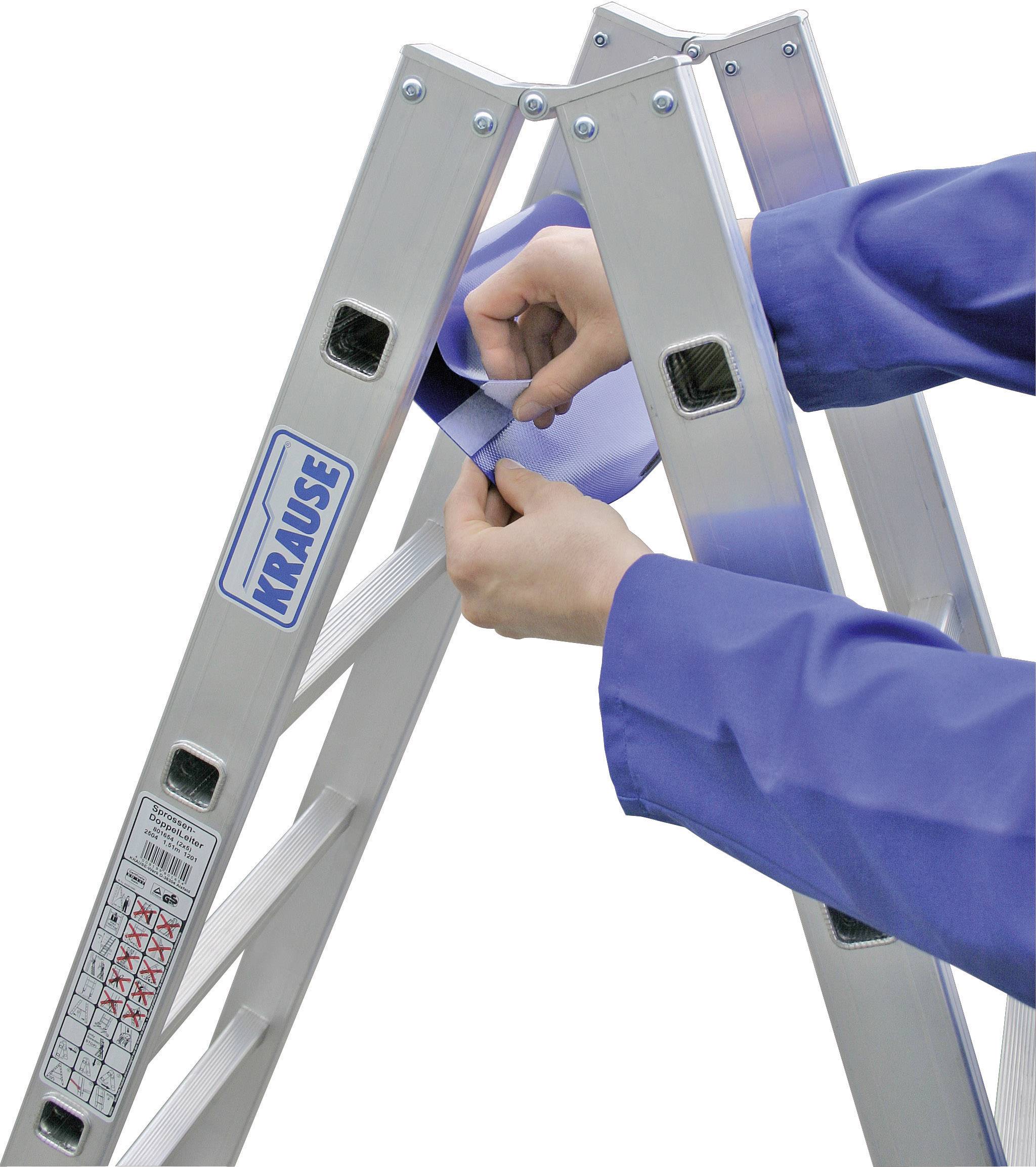 Osoba w niebieskim kombinezonie roboczym zabezpiecza składaną drabinę, aby zapewnić jej stabilność.