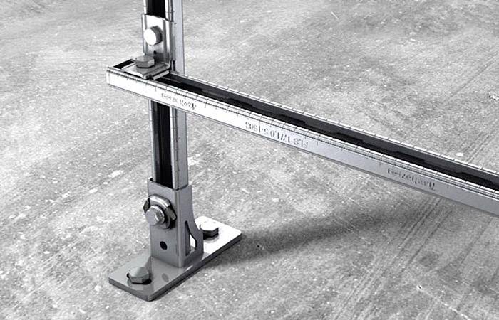 Metalowy kątownik zamocowany na podłodze betonowej, prezentujący stabilność i funkcjonalność elementów mocujących stosowanych w przemyśle.