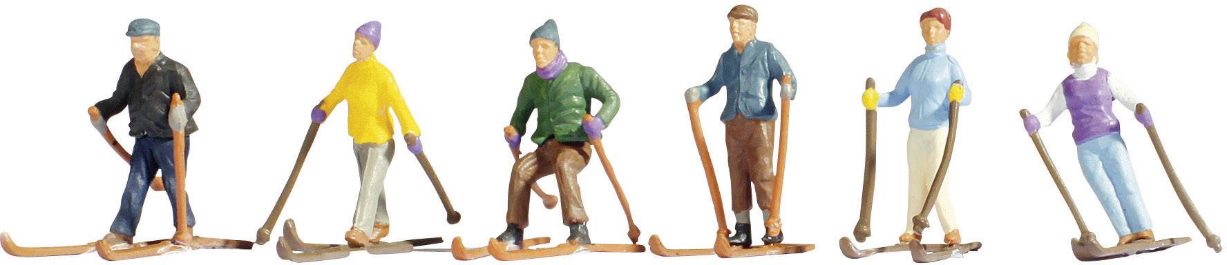 Sześć miniaturowych figurek narciarzy w kolorowych strojach, każda z nartami i kijkami narciarskimi, na białym tle.