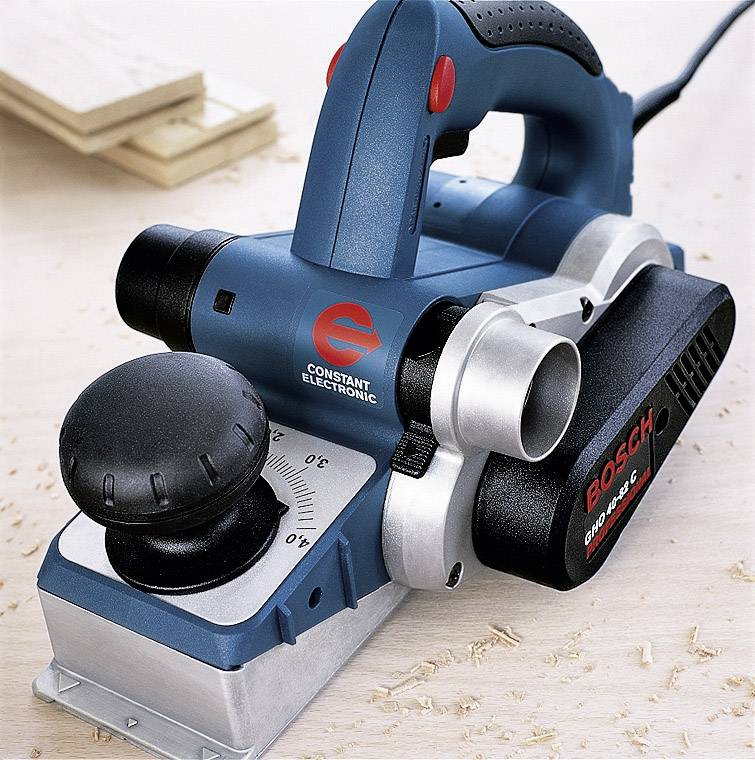 Elektryczny ręczny hebel firmy Bosch na warsztacie, otoczony wiórami drewnianymi. Jest używany do prac stolarskich.