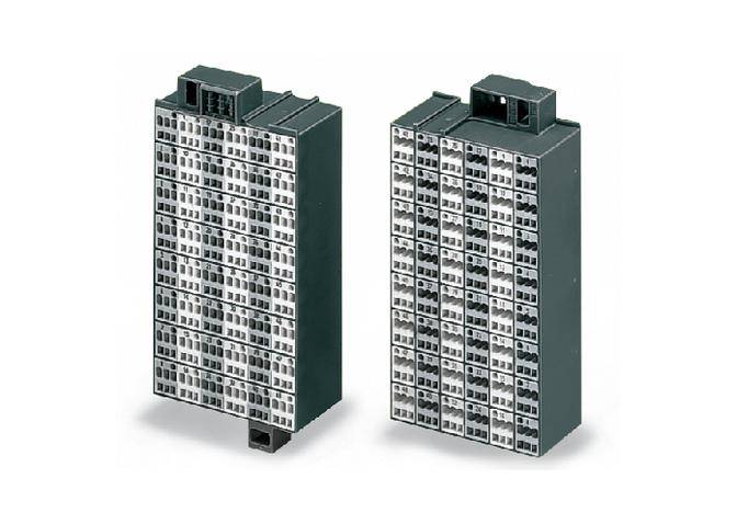 Dwa czarne elektryczne bloki zaciskowe z wieloma zaciskami, używane do prowadzenia przewodów w szafkach elektrycznych.