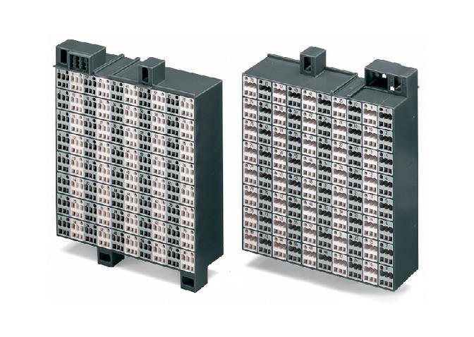 'Dwie elektroniczne komponenty z wieloma złączami, przedstawione w rzędzie. Obudowy są prostokątne i szare.'