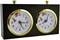 Dwie zegary szachowe obok siebie, oba ze złotymi ramkami. Jeden wskazuje godzinę 10:10, drugi 8:07. Mają czerwone wskazówki sekundowe.
