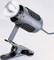 Szara lampa biurkowa z zaciskiem, o nowoczesnym designie i regulowanej głowicy, przeznaczona do zamocowania na różnych powierzchniach.