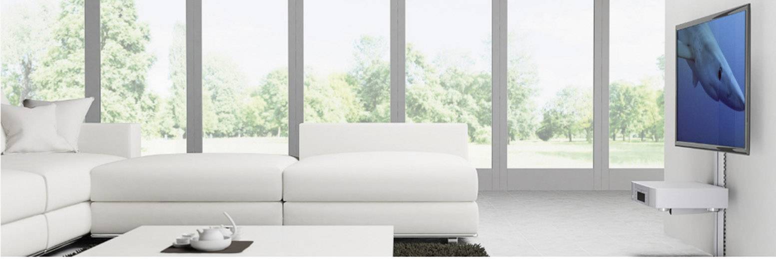 Jasny salon z dużymi oknami, białą sofą i telewizorem naściennym, na którym wyświetlony jest obraz nurkującego rekina.