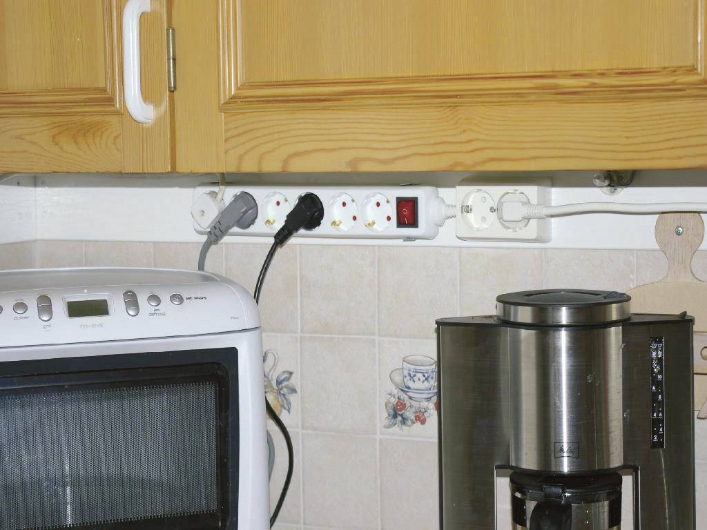 Listwa zasilająca w kuchni z podłączonymi urządzeniami: piekarnik i ekspres do kawy. Przełącznik listwy włączony na 'Włączone'.