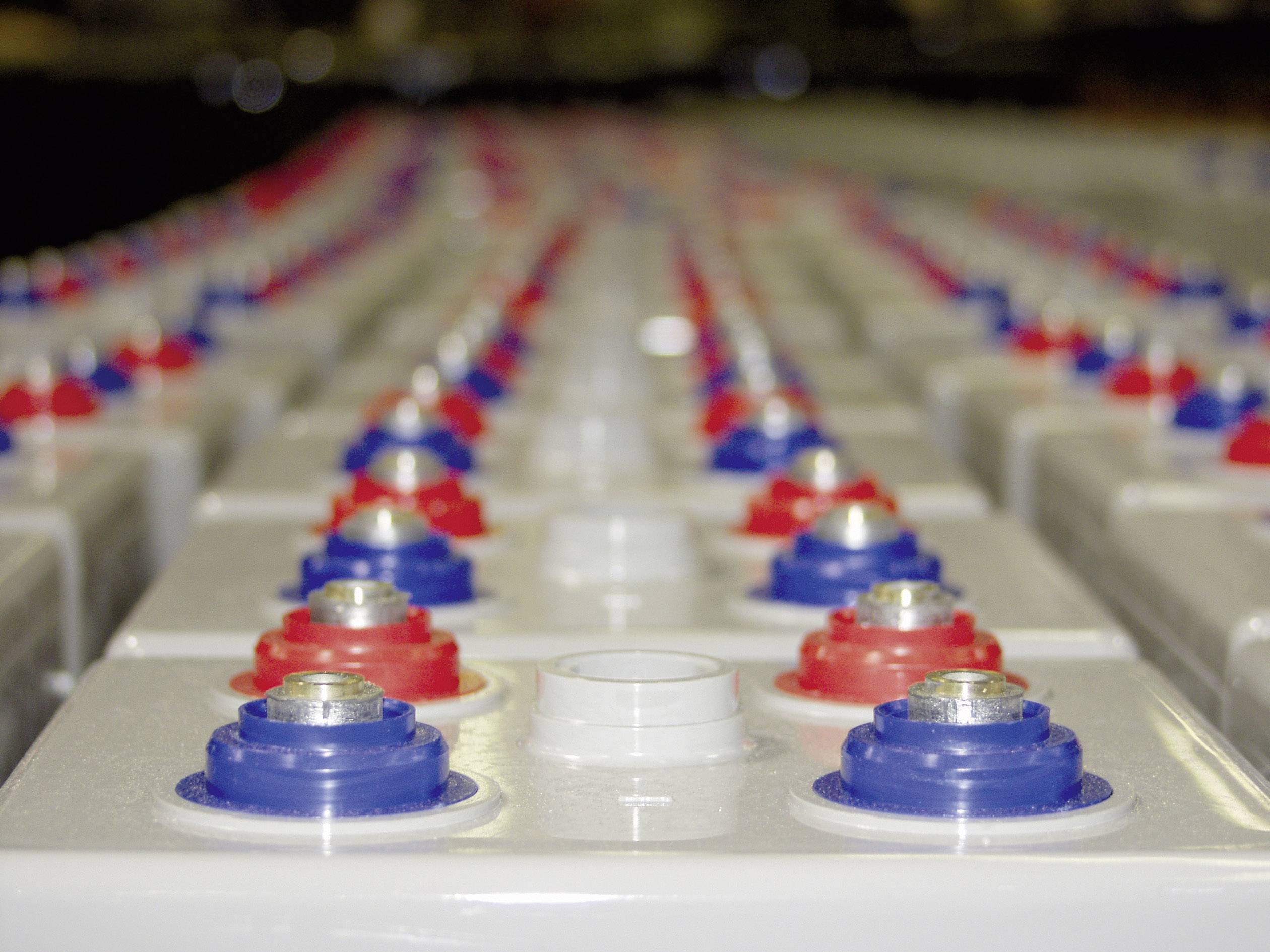 Seria przemysłowych ogniw bateryjnych z naprzemiennie czerwonymi i niebieskimi nakładkami w zakładzie produkcyjnym.