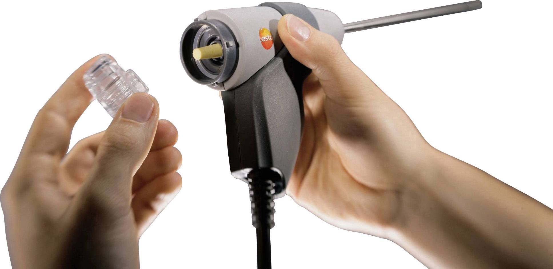 Jedna ręka trzyma pułapkę kondensatu, podczas gdy druga obejmuje szary uchwyt z metalowym prętem i przewodem.