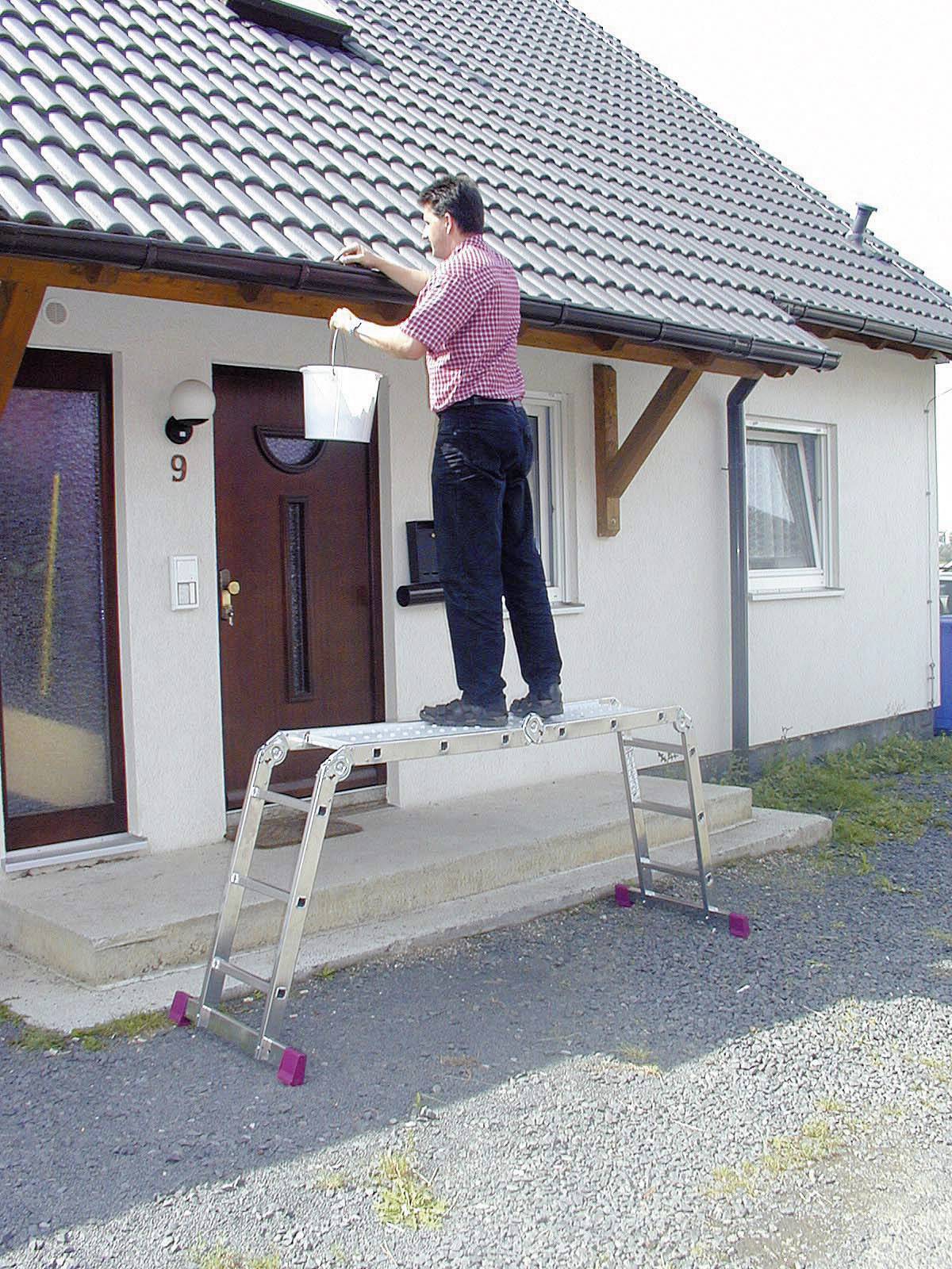 Osoba stoi na drabinie i pracuje na dachu domu.