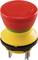 Czerwony wyłącznik awaryjny z żółtą podstawą i metalowymi złączami, służący do przerwania dopływu prądu w sytuacjach awaryjnych.