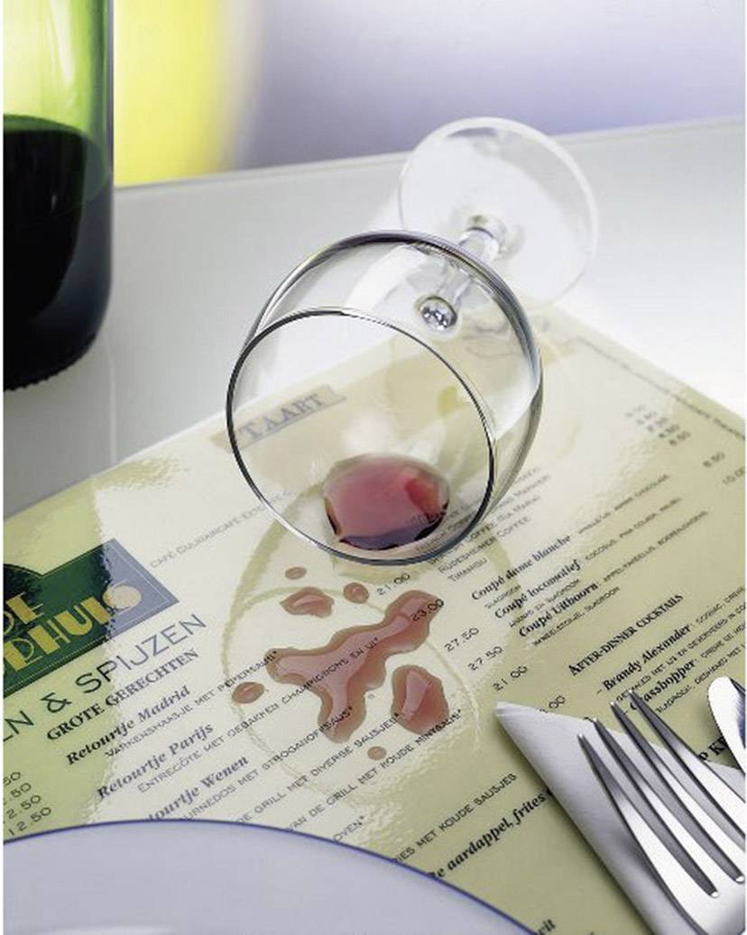 Przewrócony kieliszek wina na stole restauracyjnym, z którego czerwone wino rozlewa się na kartę menu. Obok leżą nóż i widelec.
