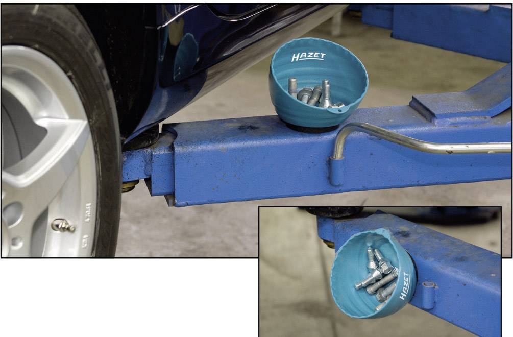 Niebieskie naczynie firmy Hazet zawierające śruby leży na podnośniku samochodowym, w pobliżu opony.