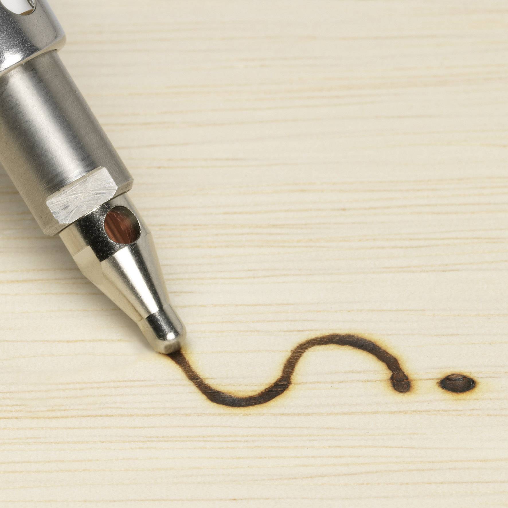 Czubek pręta paliwowego na drewnie z zakrzywioną, ciemną linią spalenizny.