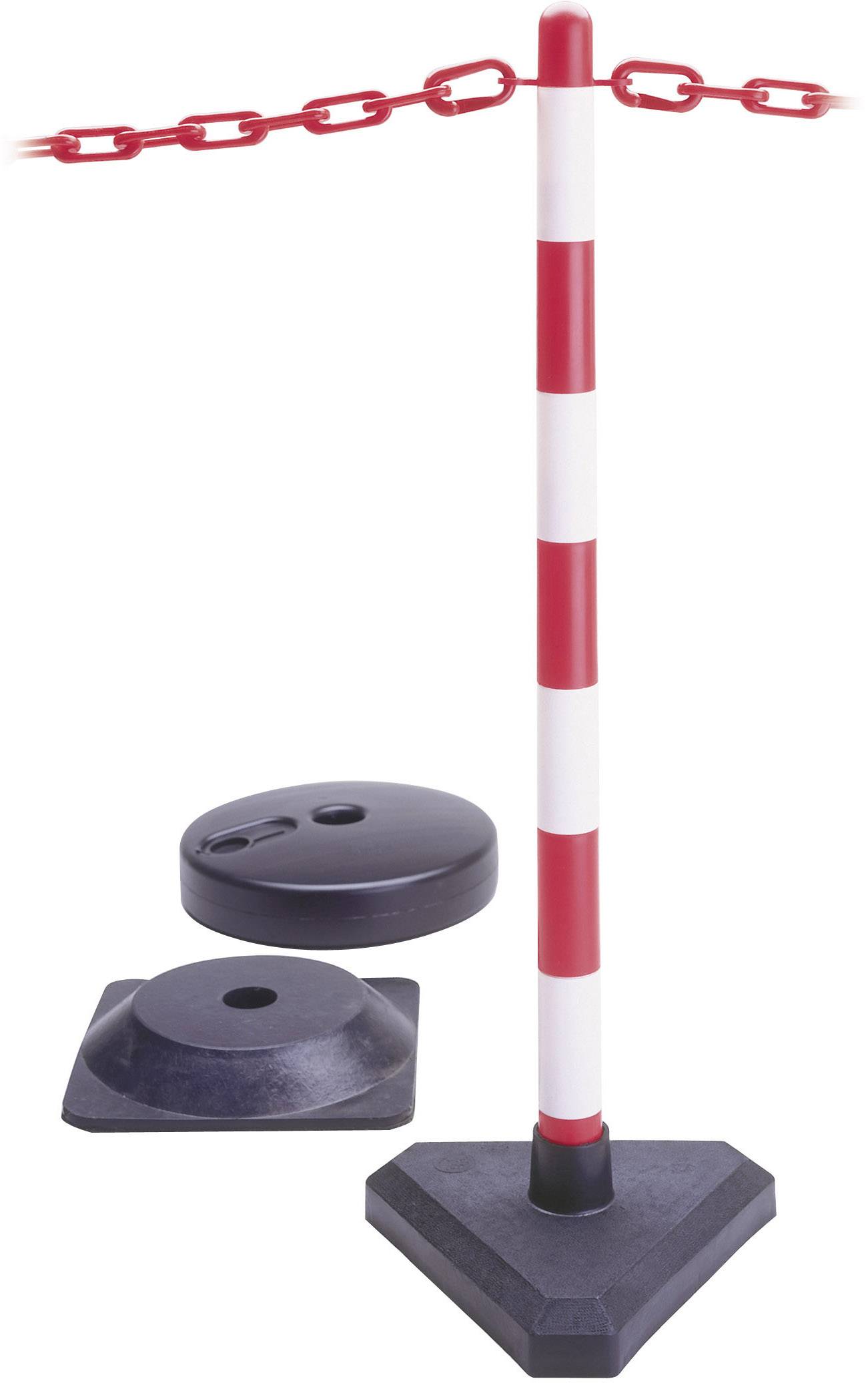 Czerwono-biała bariera z łańcuchem w kolorze czerwonym, obok której znajdują się czarne obciążniki stabilizujące, ustawiona na terenie budowy lub w strefie bezpieczeństwa.