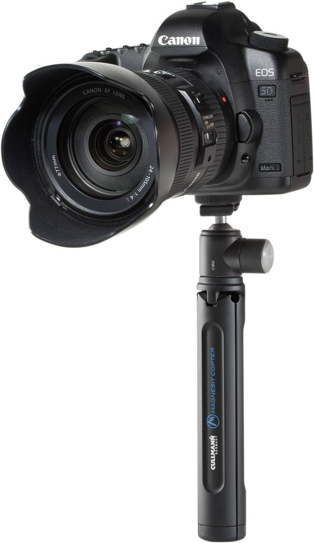 Cyfrowy aparat fotograficzny Canon EOS 5D Mark II z założonym obiektywem i przymocowanym do niego monopod, na białym tle.