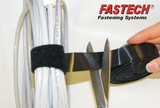 Zväzok káblov je pripevnený čiernou suchým zipsom. Nožnice prestrihávajú pásik. Vpravo hore je logo 'FASTECH Fastening Systems'.