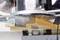 Horná fréza opracúva kus dreva. Drevené triesky lietajú do vzduchu. Zariadenie obsluhuje jedna osoba, dôraz je kladený na stroj.