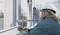 Stavebný robotník montuje oceľovú nosnú konštrukciu na stavenisku. Má na sebe ochranný pracovný helm a pracovný odev.
