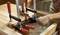 Dve ruky upevňujúce drevo pomocou viacerých svoriek na pracovnom stole. Vodováha kontroluje vyrovnanie.