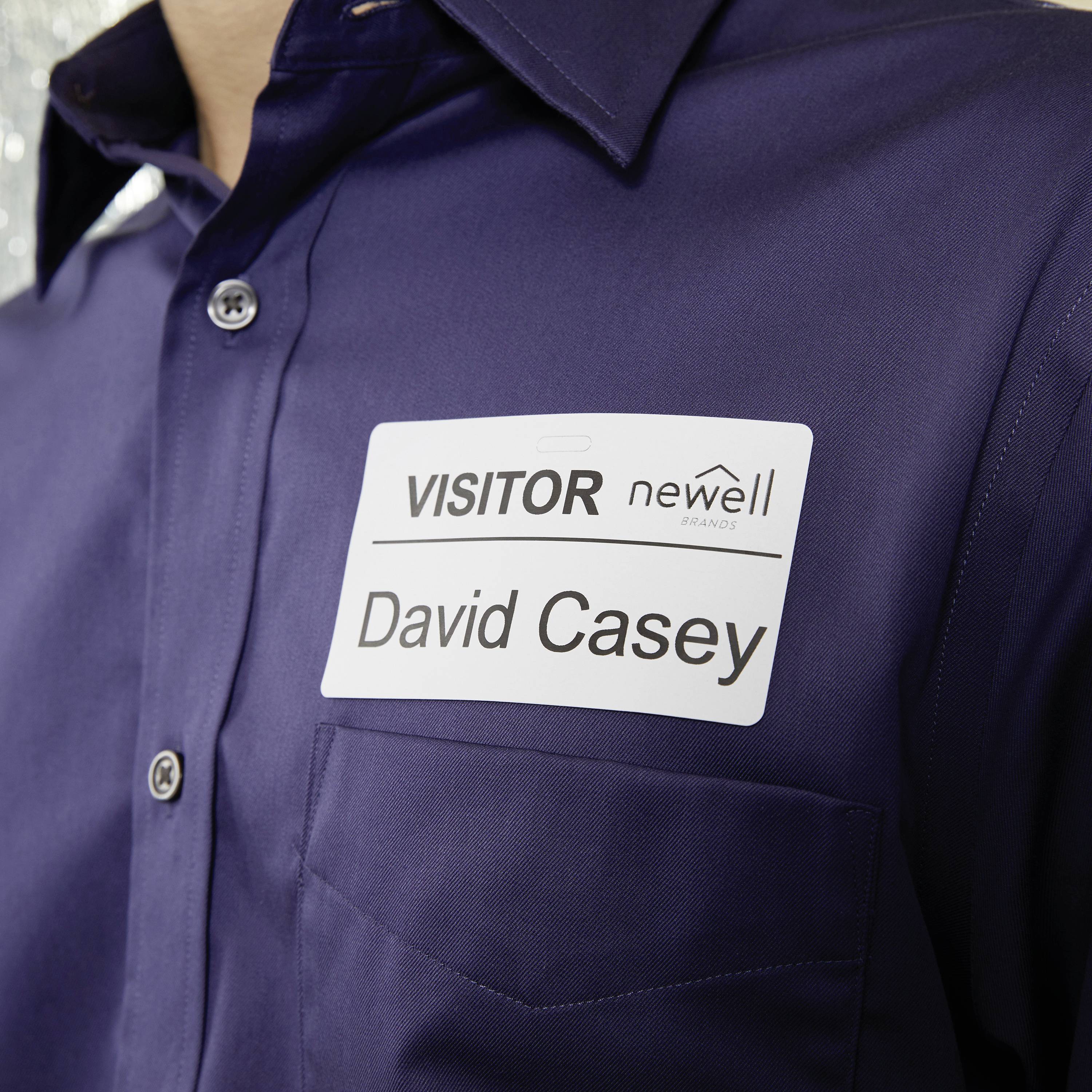 Muž má na hrudi visačku s nápisom 'NÁVŠTEVNÍK David Casey'.