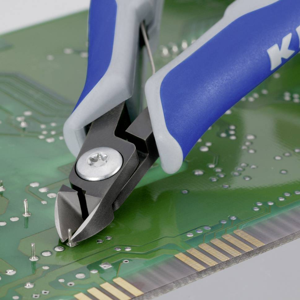 Kliešte strihajú drôty na doske plošných spojov, čo ukazuje elektronickú opravu alebo montáž.