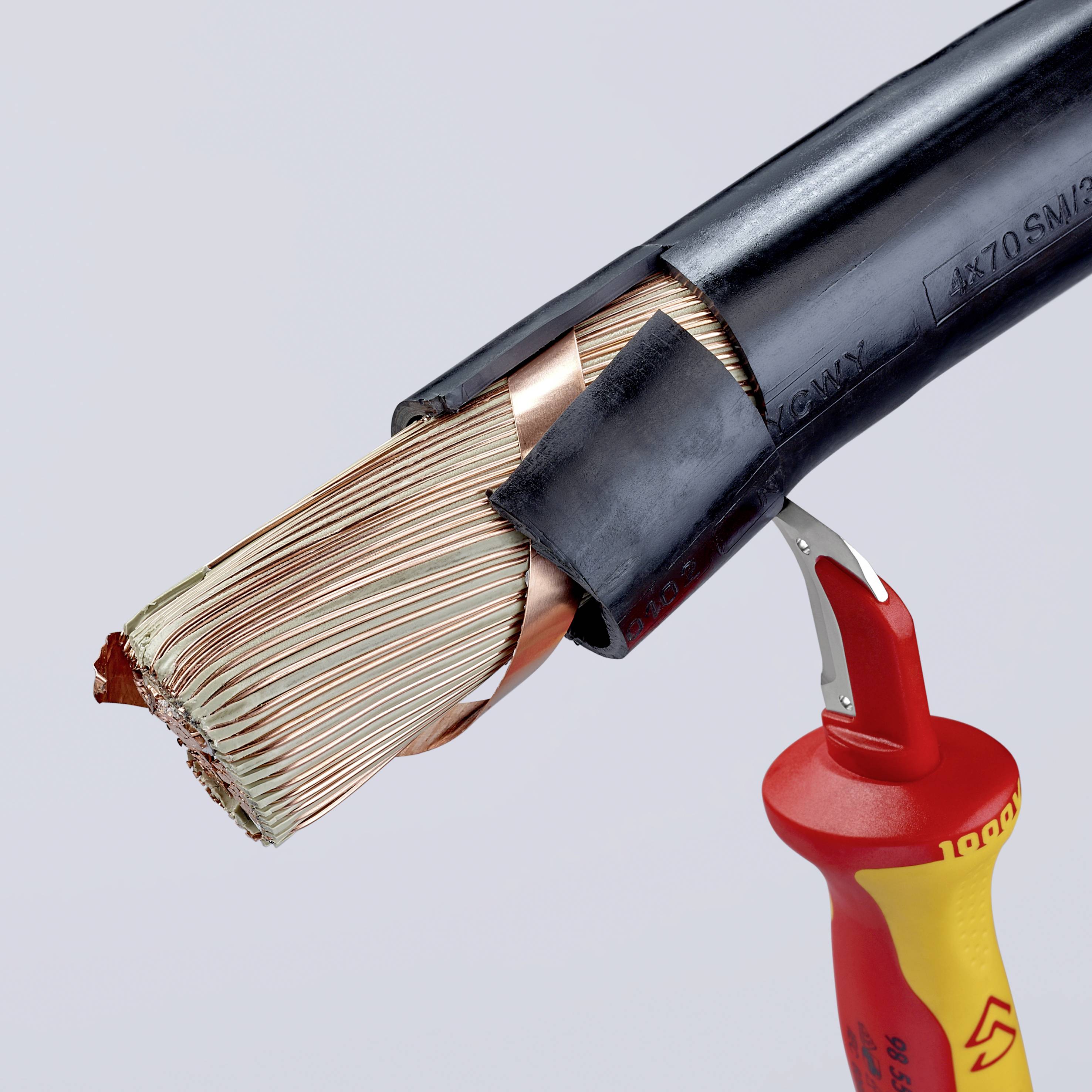 Červený nástroj reže hrubý čierny elektrický kábel s odhaleným medeným vodičom.