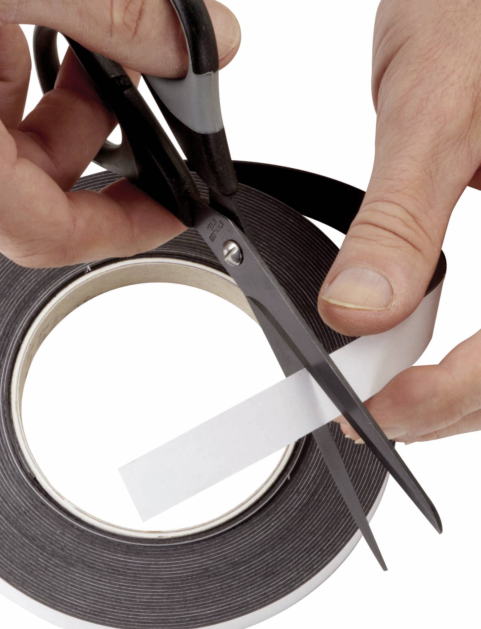 Dve ruky strihajú kus lepiacej pásky z rolky. Scéna ukazuje presné použitie nožníc.