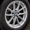 Detailný záber strieborného pneumatiky automobilu BMW s modro-bielym logom na ráfiku, nainštalovaný na vozidle.
