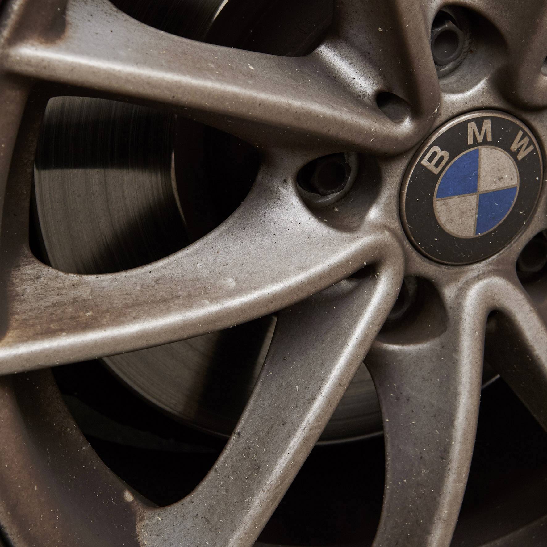 Detailný záber špinavého kolesa BMW s viditeľným logom v strede.