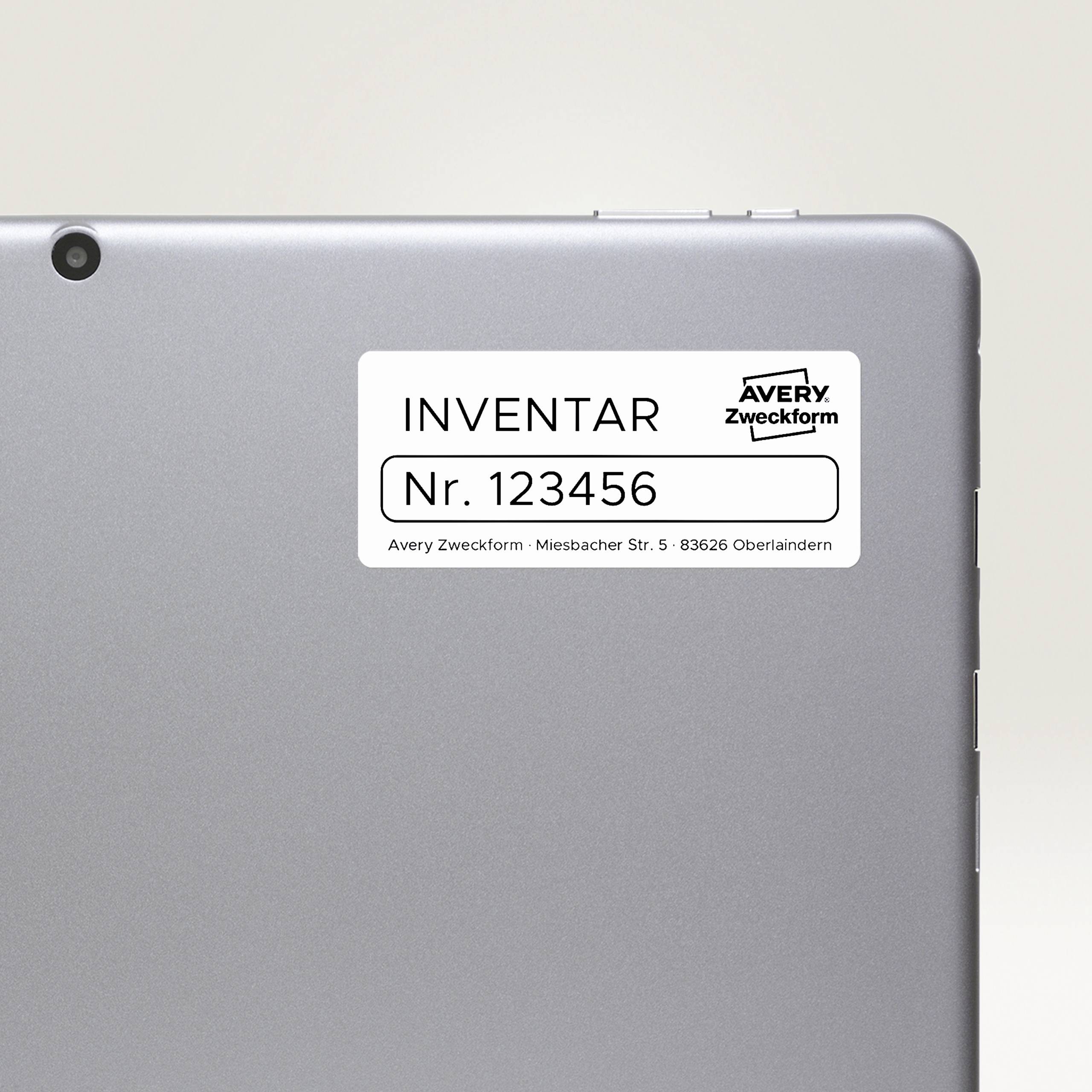 Zadná strana tabletu s bielou etiketou, označenie 'INVENTÁR č. 123456', výrobca Avery Zweckform.