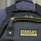 Čierny ruksak so žltým logom 'STANLEY FATMAX'. Zips má prívesok s nápisom 'STANLEY'.
