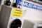 Výstražná tabuľa vedľa komponenty PV systému s varovaním 'WARNING PV SYSTEM'. V pozadí rozmazaná Marlec PV nálepka. Hlavný dôraz na bezpečnostný pokyn.