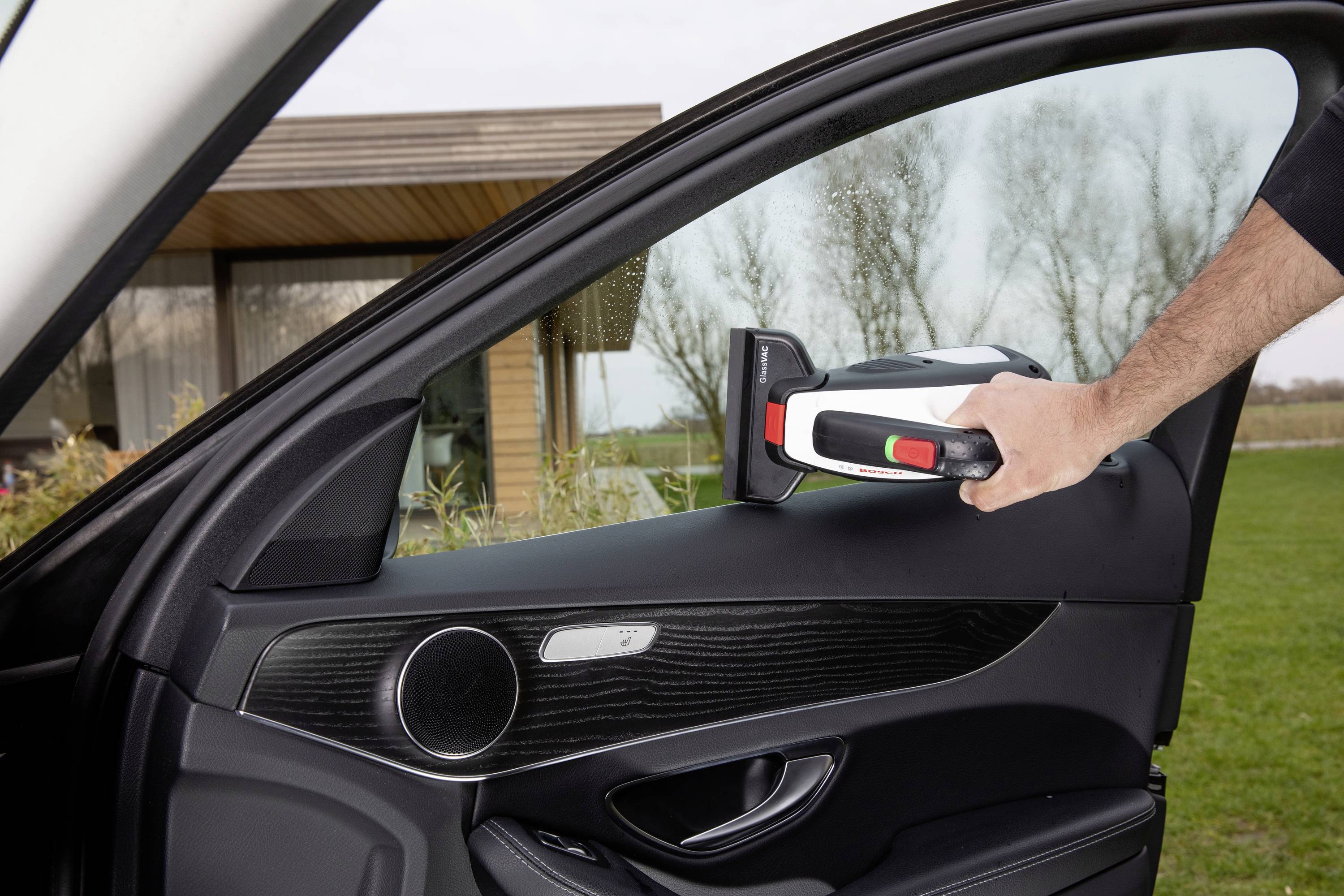Osoba otvára dvere auta s prenosnou nabíjačkou pre elektromobily vonku pred moderným domom.